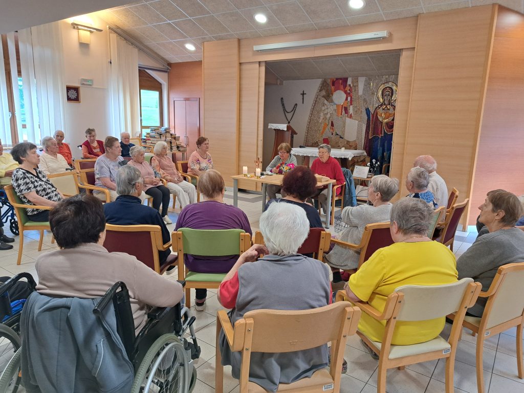 Na sliki je skupina starejših oseb, pri molitvi.