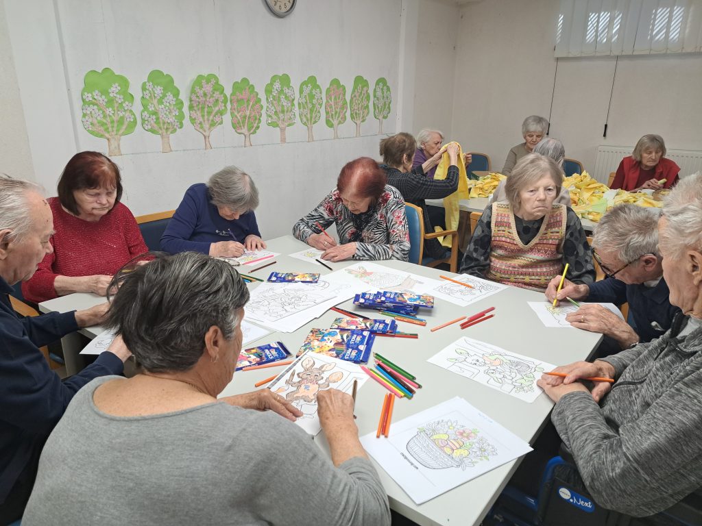 Na sliki je skupina starejših oseb ki barvajo.