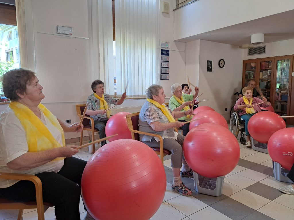 Na sliki je skupina starejših oseb, članov benda, med nastopom.