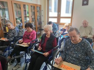 Na sliki je skupina starejših oseb med igranjem tombole.