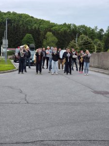Na sliki je skupina ljudi, ki igrajo na pihala.
