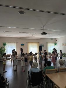 Slika prikazuje nastopajočo skupino osnovnošolk, ki izvajajo plesni nastop.