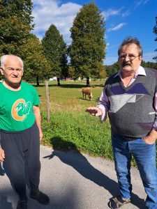 Na sliki sta dve starejši osebi v naravi. V ozadju je konj.